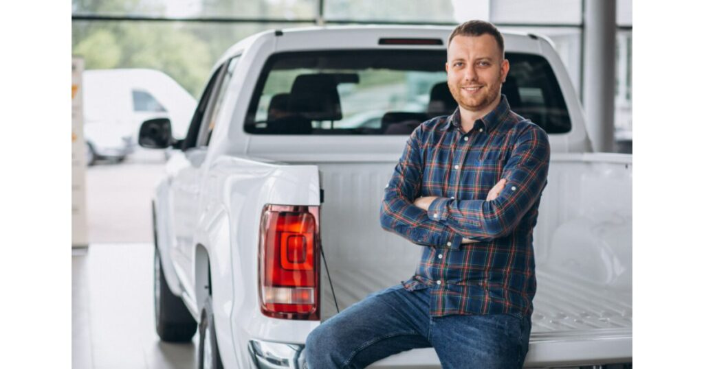 Hombre de negocios apoyado en tolva de pickup blanca, representando los beneficios del renting empresarial de camionetas en Costa Rica