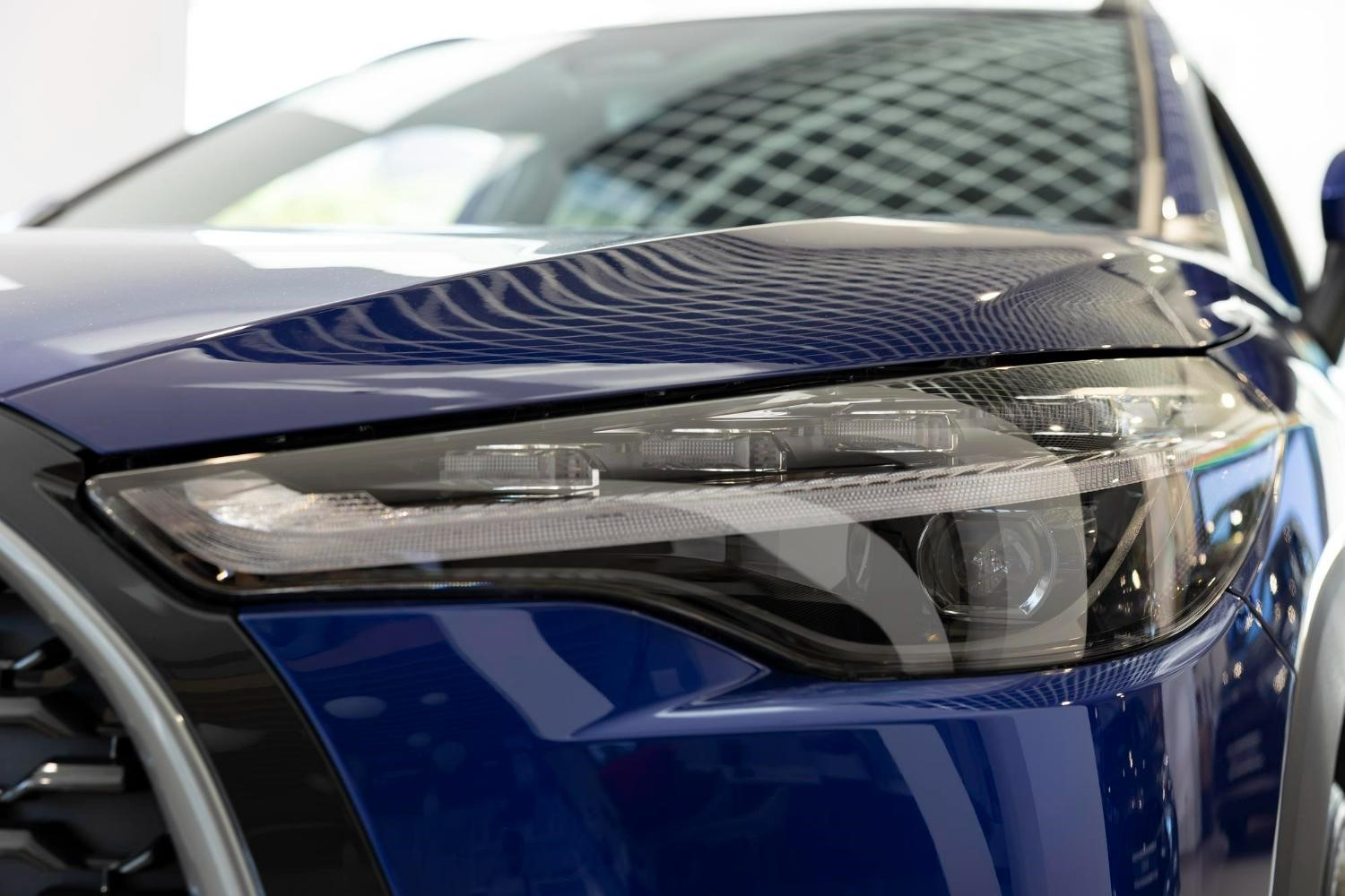 Plano detalle de un faro LED delantero y la parrilla frontal de un automóvil azul de estilo moderno.