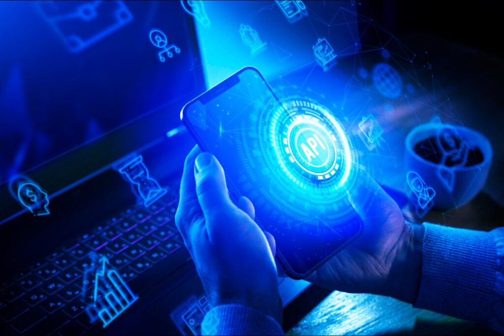 Hombre sosteniendo un smartphone con holograma de API y elementos digitales