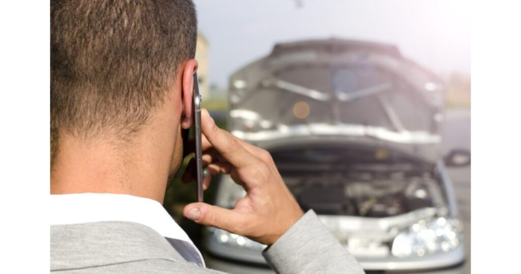 Ejecutivo reportando por teléfono un siniestro de flota vehicular con vehículo averiado al fondo, protocolo de gestión de accidentes con Total Fleet Costa Rica
